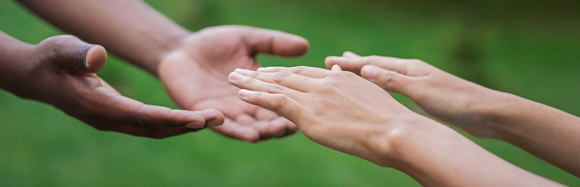 Two people extending their hands towards each other in support