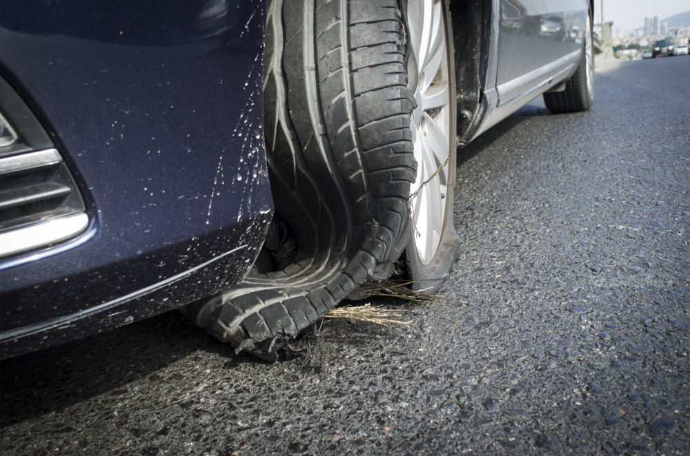 Close-up of vehicle with ruined tire on the highway