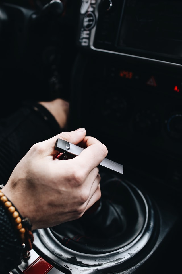 Person holds a JUUL vaping device in a car
