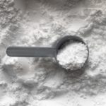 A cup of talcum powder sits atop a large pile of talc.