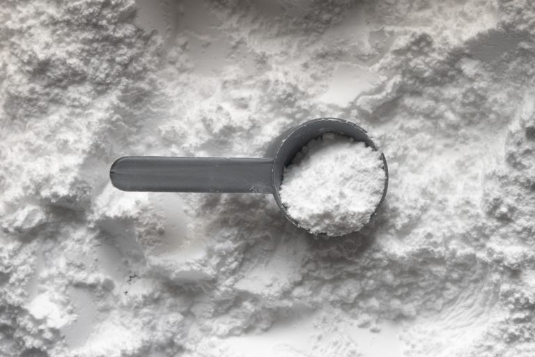 A cup of talcum powder sits atop a large pile of talc.