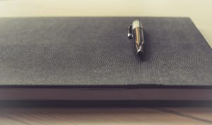 A notebook and pen laying on a table