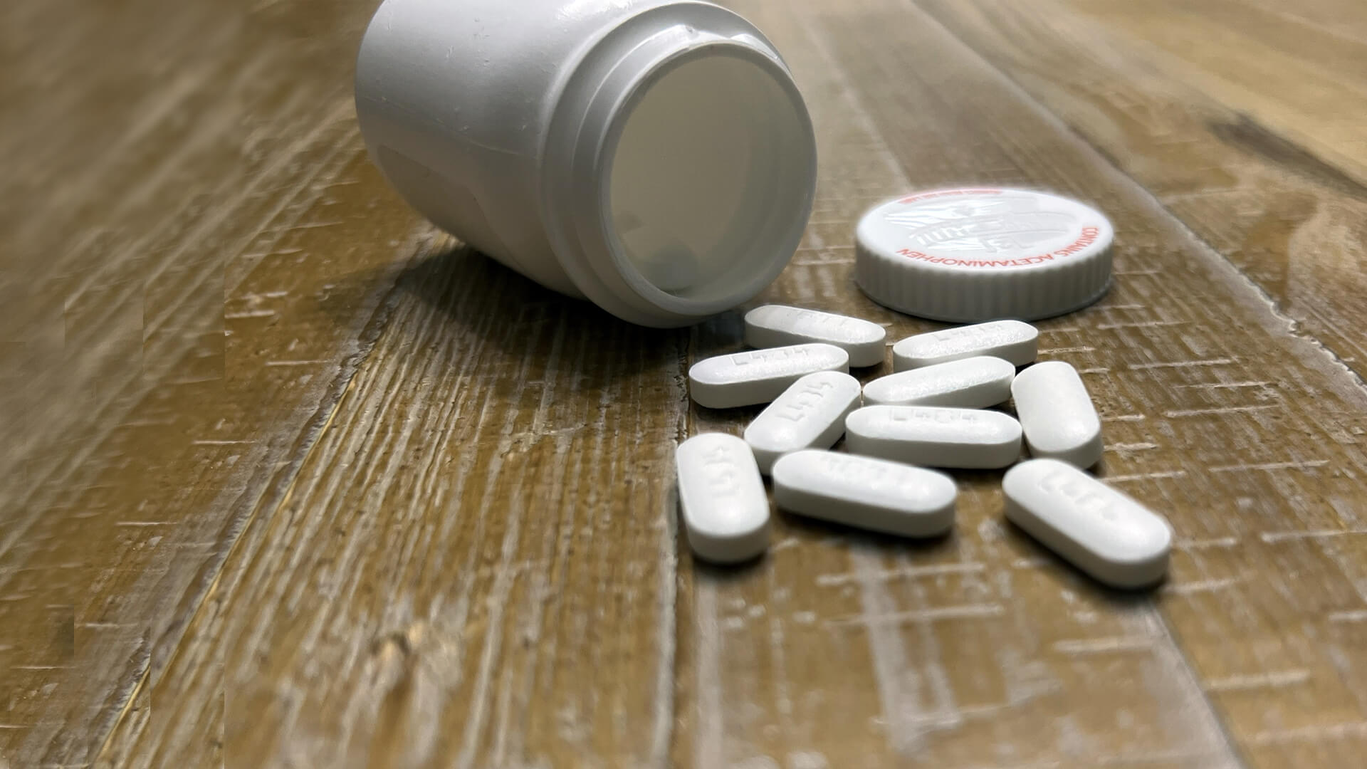 Bottle of acetaminophen, with pills spilled on the ground.