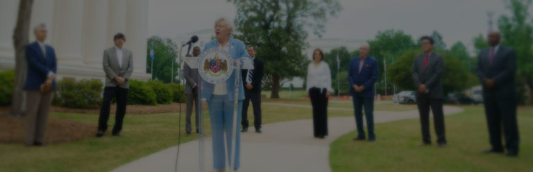 Gov. Kay Ivey speaks at a podium to discuss the Ribbons of Hope Campaign