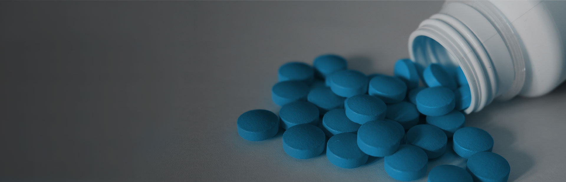 Small blue pills spilling out of a bottle