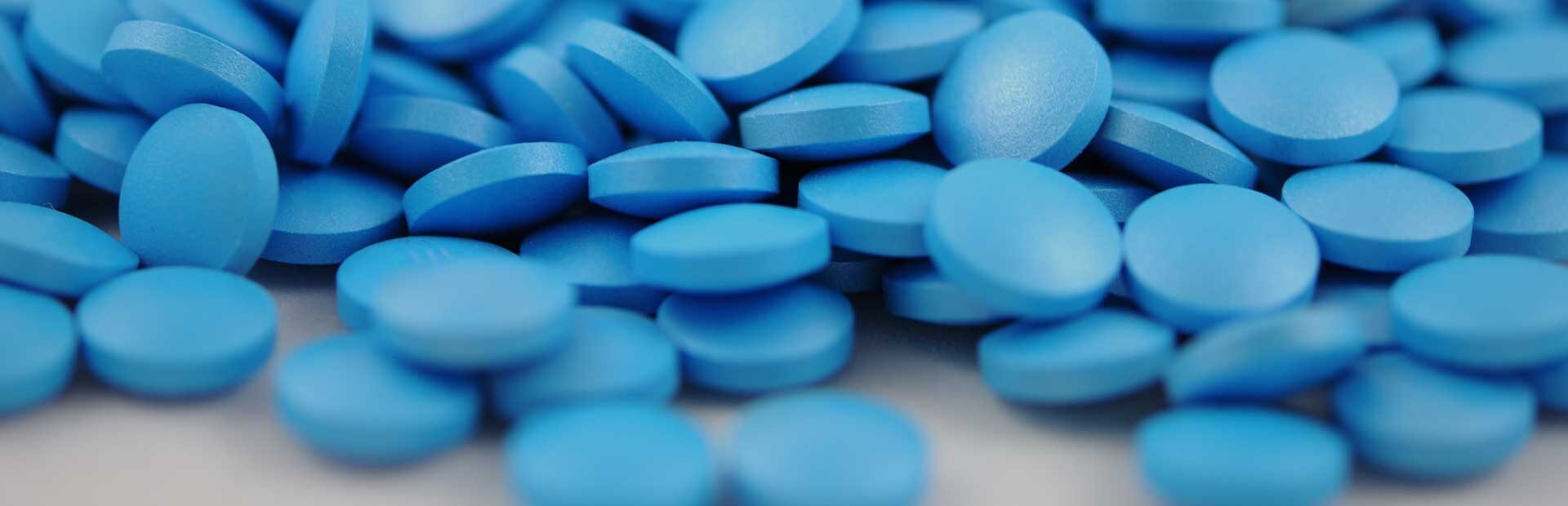 A loose pile of small round blue pills