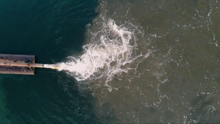 Contaminated water flowing into an ocean/river from a pipe