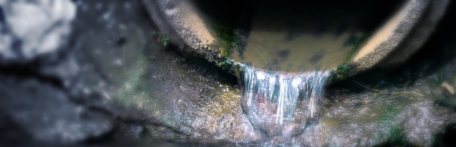 Contaminated water flows from a pipe into a body of water