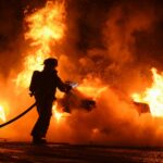 Firefighter works to extinguish fire engulfing vehicle in flames