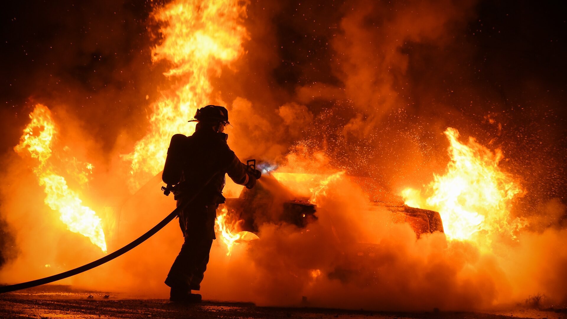 Firefighter works to extinguish fire engulfing vehicle in flames