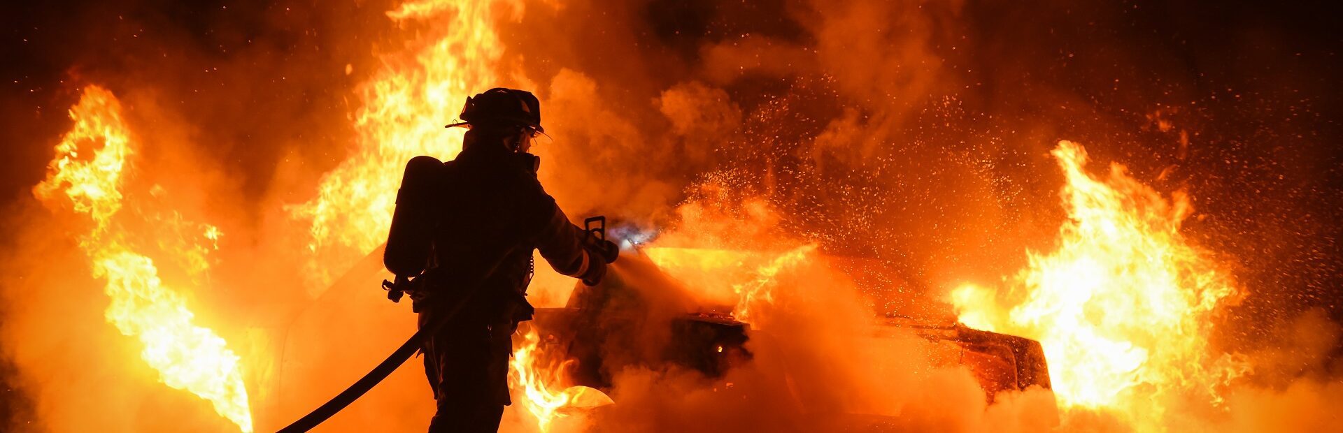 Firefighter works to extinguish fire engulfing vehicle in flames