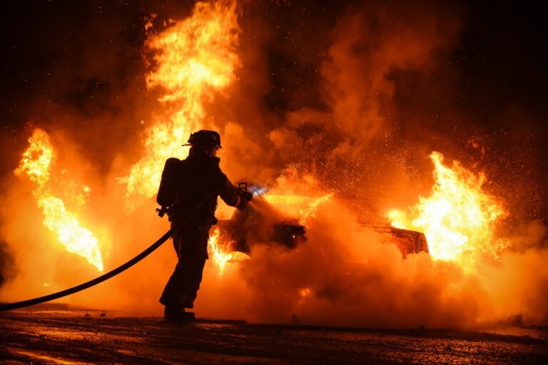 Firefighter works to extinguish fire engulfing vehicle in flames