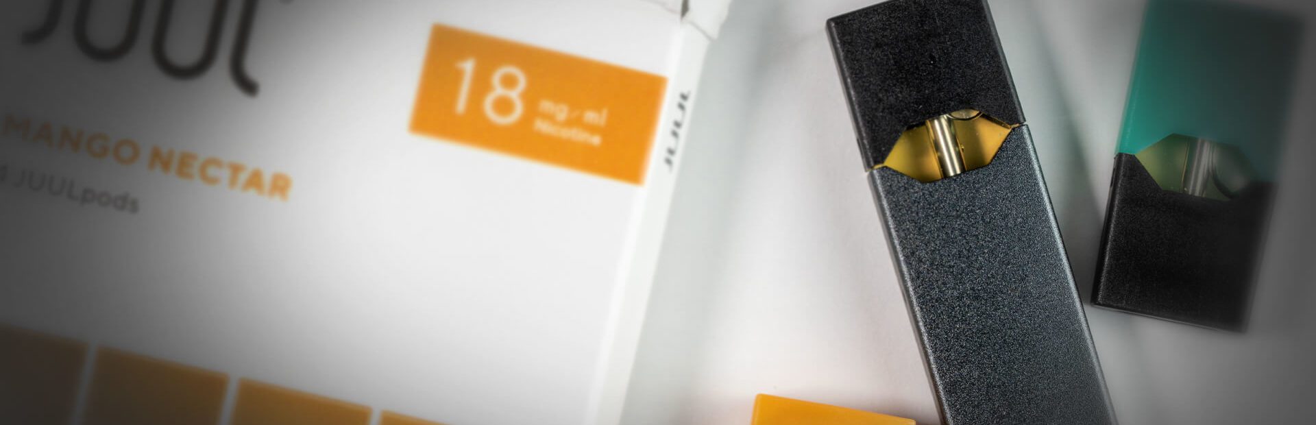 JUUL Vaping Device on a box of "Mango Nectar" flavored Cartridges