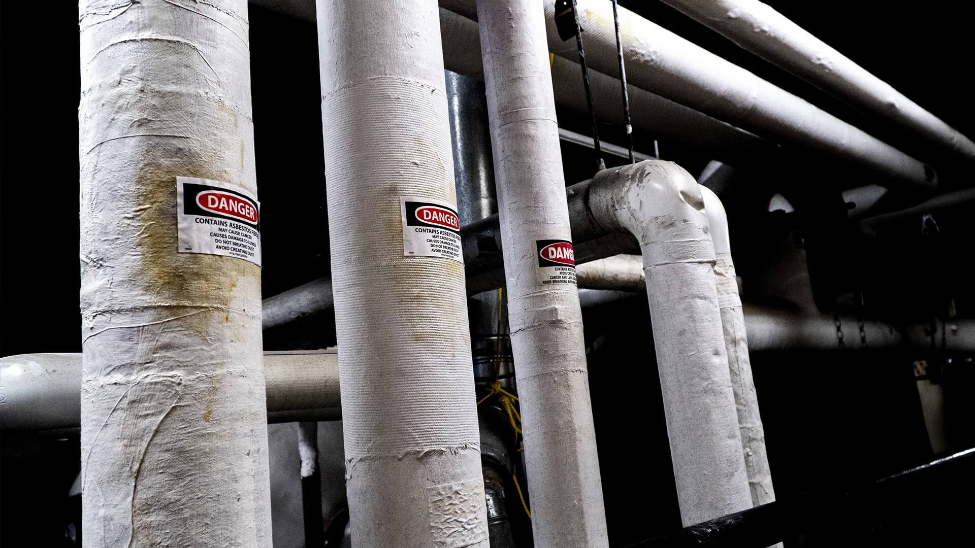 Pipes wrapped with asbestos with danger signs