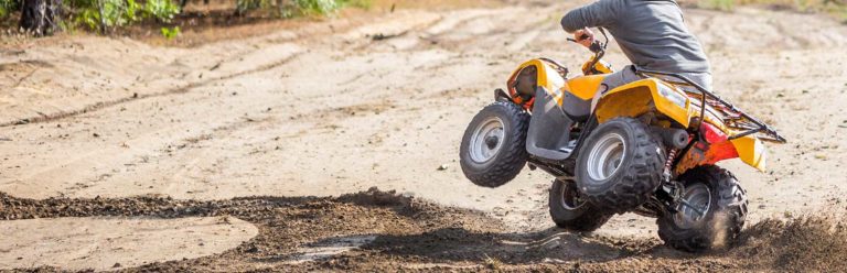 Person riding a all-terrain vehicle (ATV) through mud