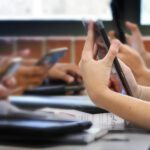 Young people looking at their phones in a school setting