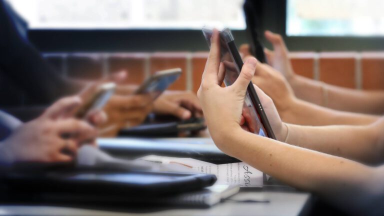 Young people looking at their phones in a school setting