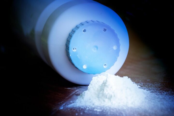 bottle of talcum powder on its side, with talc flowing out