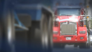 Red commercial tractor trailer truck in traffic